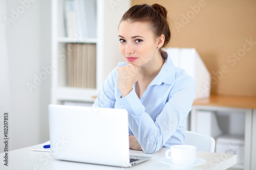 Young business woman working on laptop in office. Successful business concept.