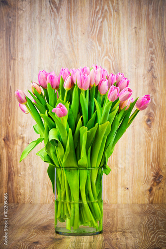 Tulips in the vase on wooden background