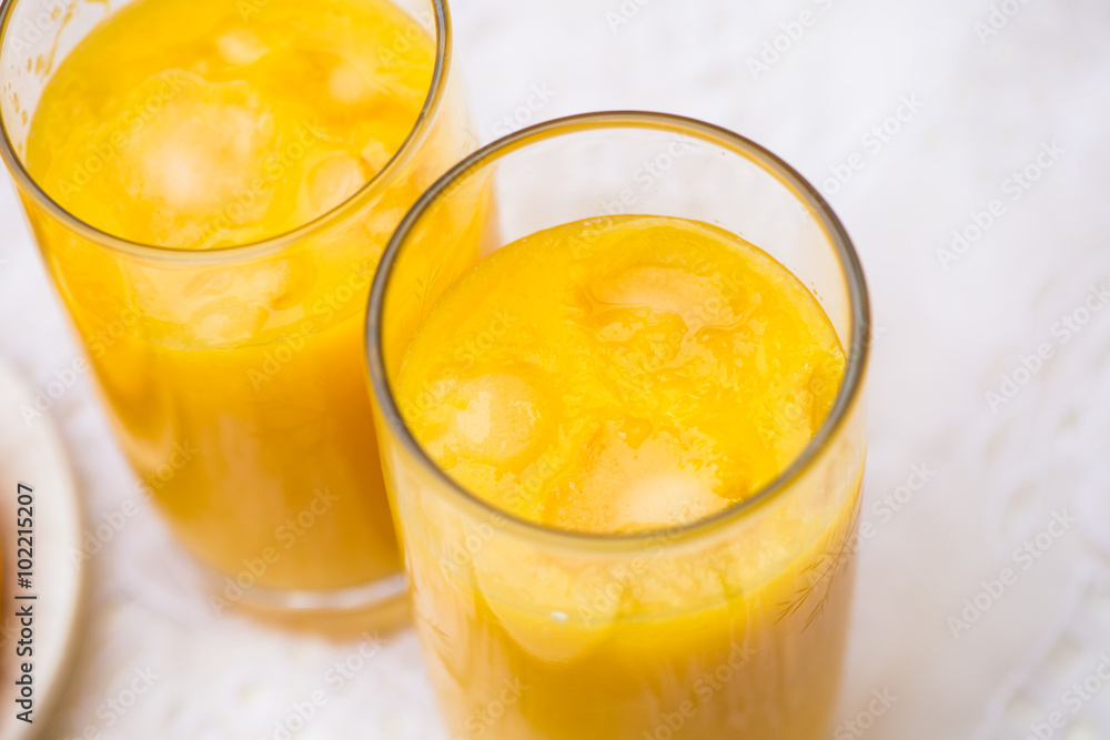 Two Glasses of Orange Juice with Ice on White