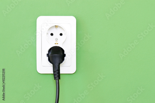 European white electrical outlet socket and black cable pluged i photo