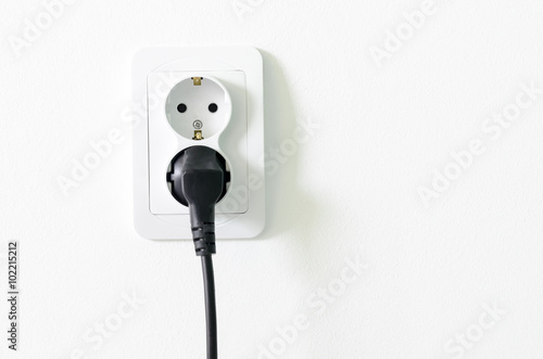 European white electrical outlet socket and black cable pluged i