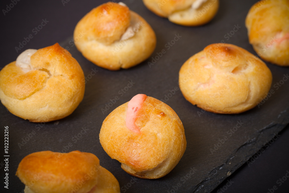 Set of small profiteroles on a black slate plate. Selective focu