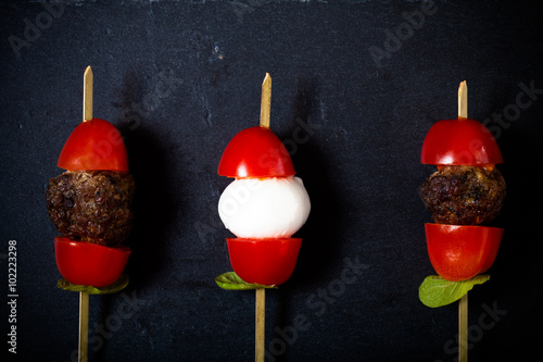 Small snacks canape with cherry tomatoes, mozzarella and meatbol