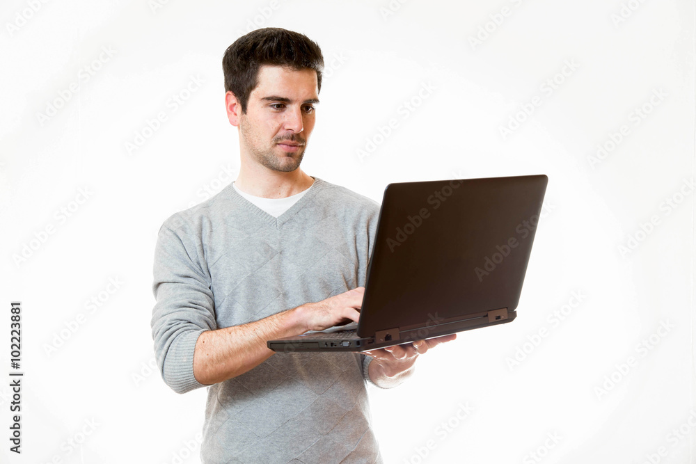 Junger Mann arbeitet im Stehen an einem Laptop Junger Mann arbeitet im Stehen an einem Laptop