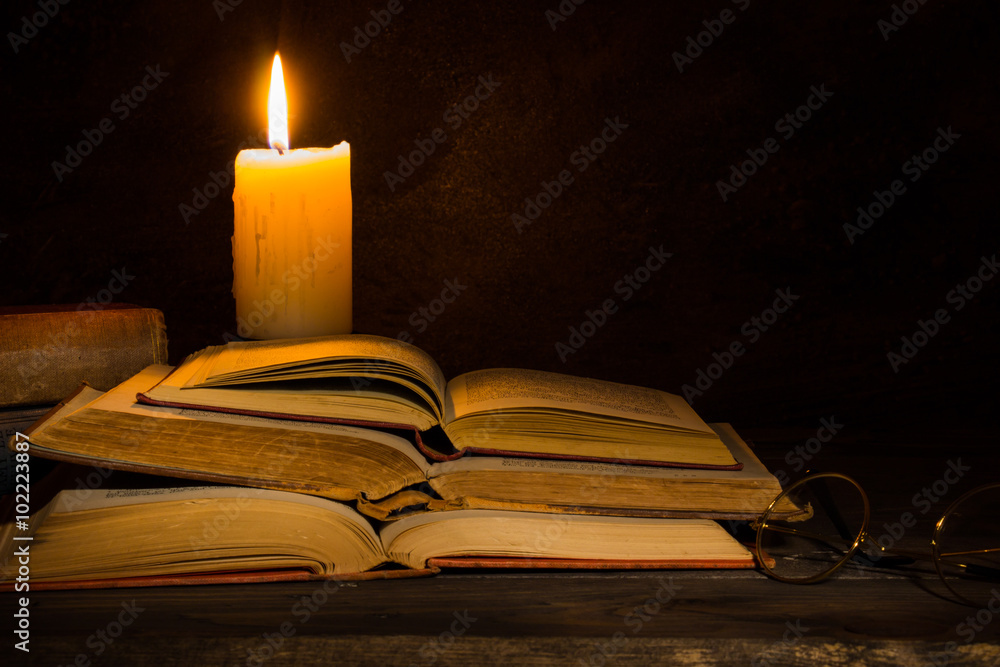 old books being read by candle light old books being read by candle light