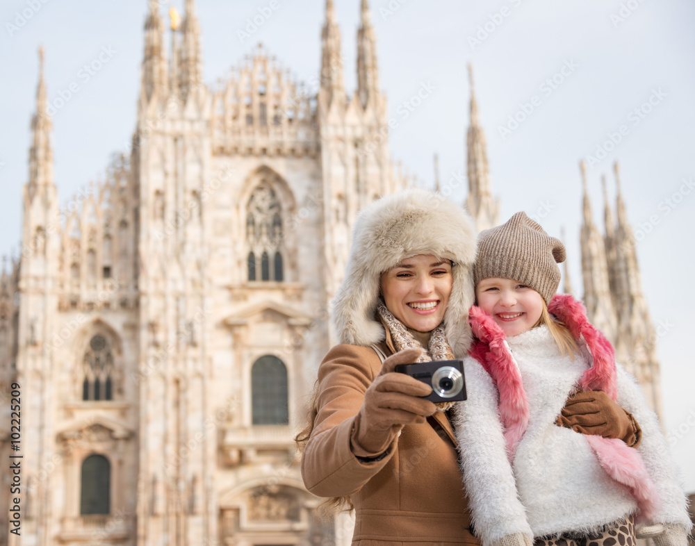 Smiling mother and daughter looking on photos near Duomo, Milan Smiling mother and daughter looking on photos near Duomo, Milan