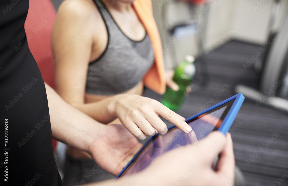 close up of trainer hands with tablet pc in gym