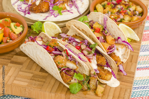 Baja Fish Tacos - Soft shell tacos filled with seasoned fried white fish served with red cabbage, pineapple salsa, chunky guacamole and creamy Baja style sauce.
