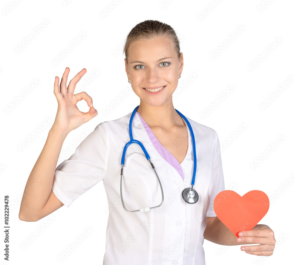 Woman intern holding paper heart in her hand and showing sign of okay Woman intern holding paper heart in her hand and showing sign of okay