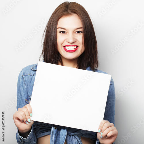 Smiling young casual style woman showing blank signboard