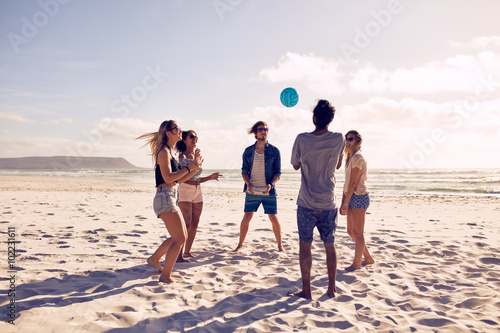 Young people playing with ball at the beach