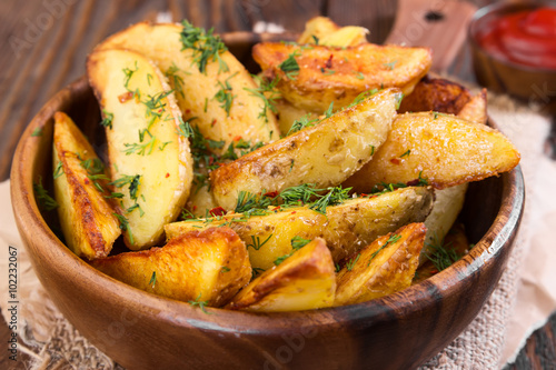 Potato wedges with dill on wooden background