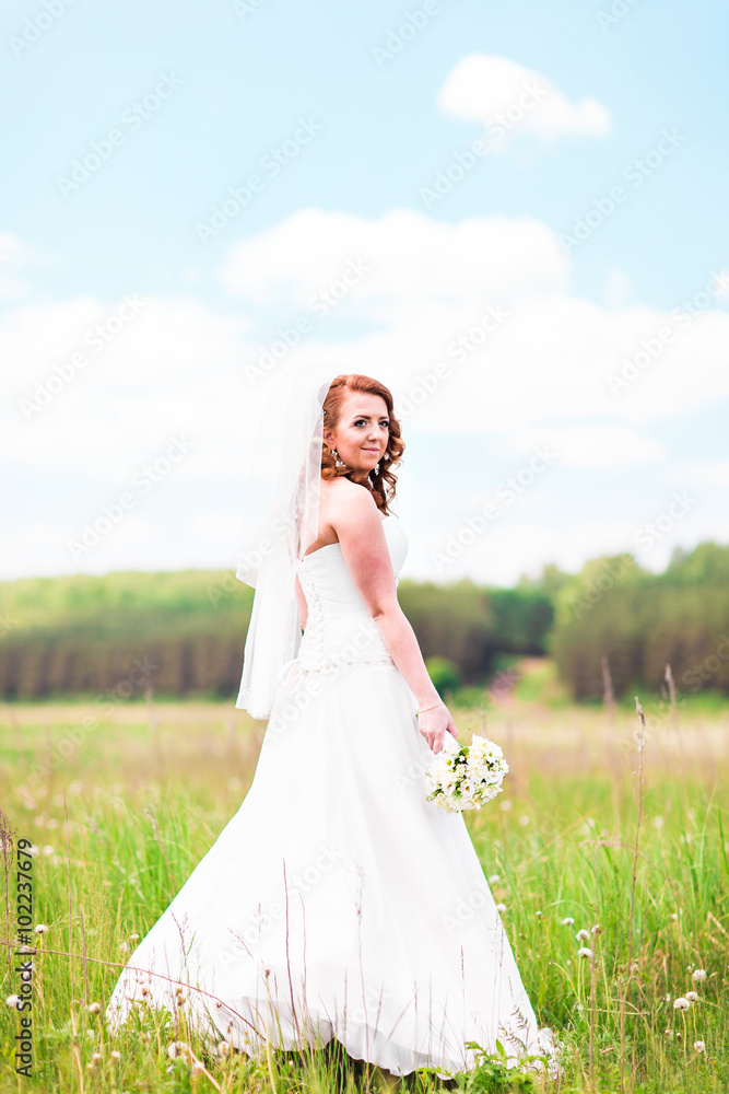 Beautiful bride with wedding bouquet of flowers outdoors in field Beautiful bride with wedding bouquet of flowers outdoors in field