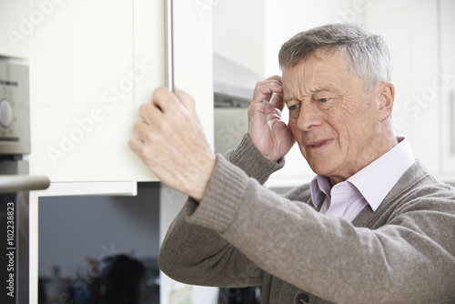 Forgetful Senior Man Looking In Cupboard photo