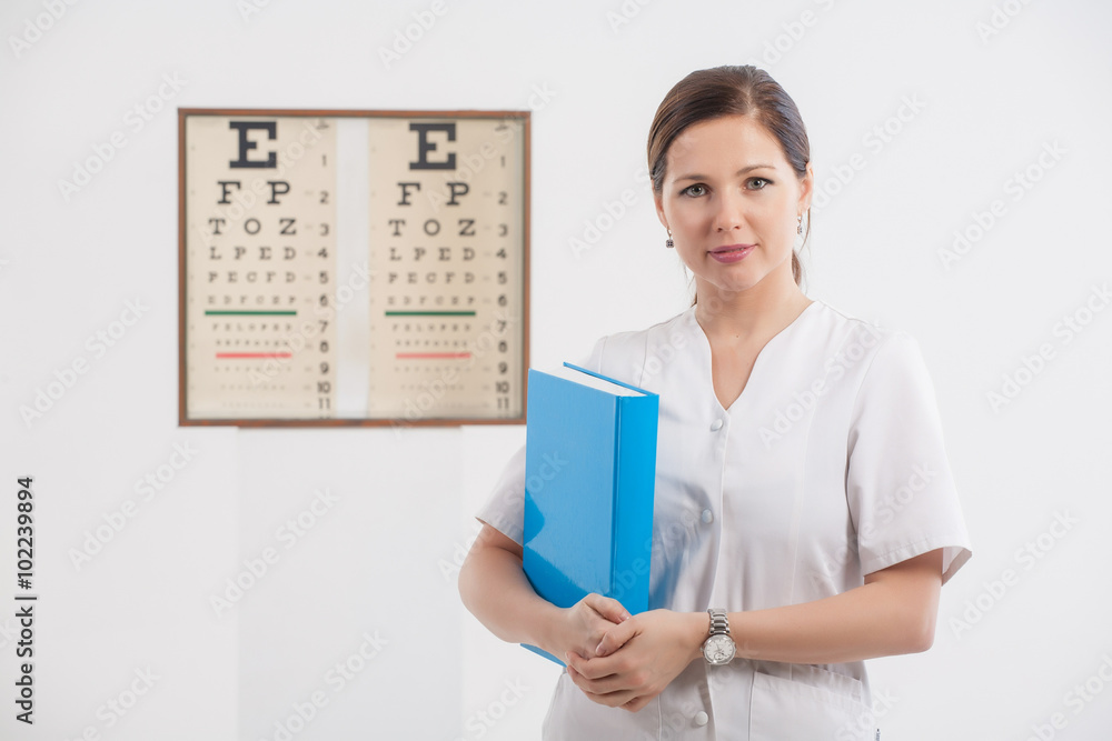 Doctor optometrist with blue book and eye chart in the backgroun Doctor optometrist with blue book and eye chart in the backgroun