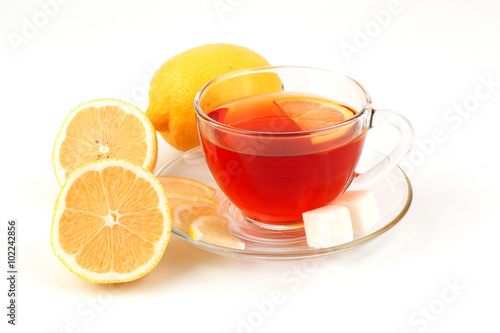 Glass cup of tea near several lemons.