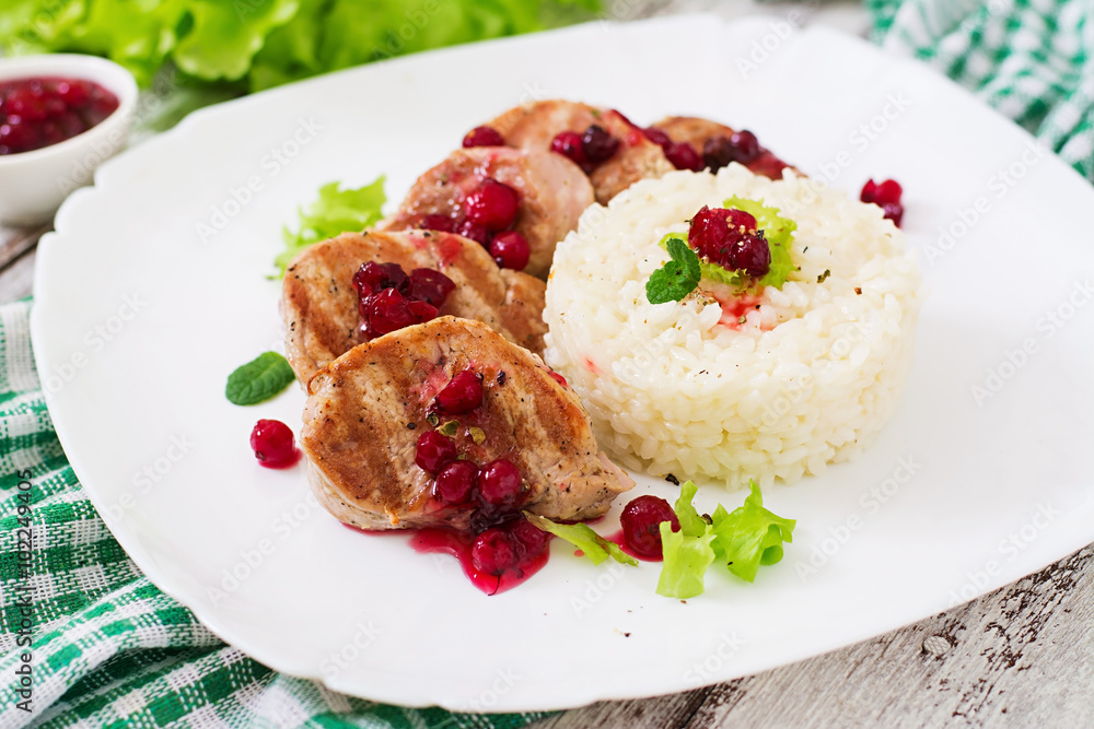 Pork medallions steak with cranberry sauce and a side dish of rice Pork medallions steak with cranberry sauce and a side dish of rice
