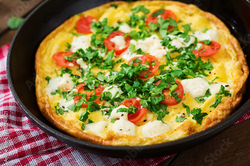 Omelet with tomatoes, parsley and feta cheese in pan