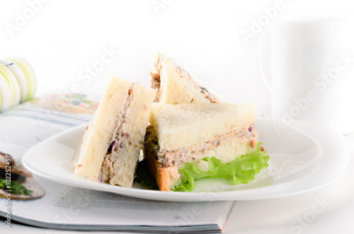 Breakfast of creamy tuna sandwiches with cup of tea and a journa