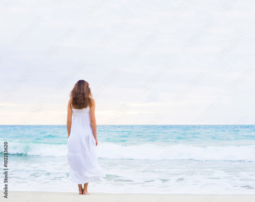 Beautiful brunette going to the wavy ocean holding her white dress. Beautiful brunette going to the wavy ocean holding her white dress.