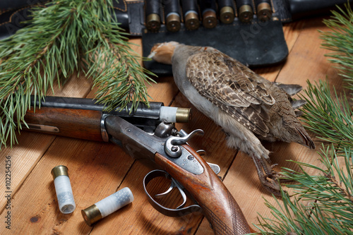 Hunting trophy - partridge, rifle, cartridge belt, ammunition, on wooden boards
