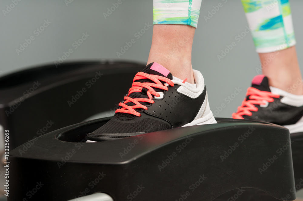 Fototapeta premium Closeup of young female feet working on stepper