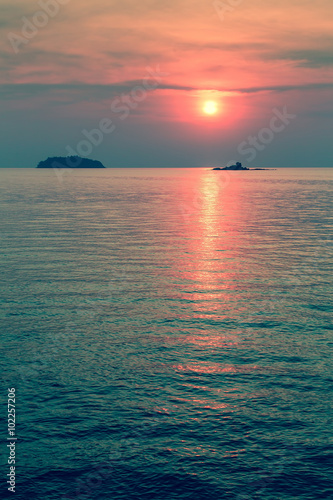Beautiful blood-red sunset in the sea with tropical Islands.