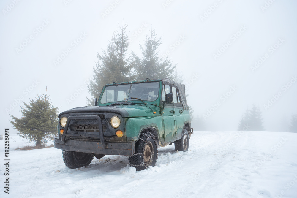 Green off-road vehicle on the snow-covered mountain Green off-road vehicle on the snow-covered mountain