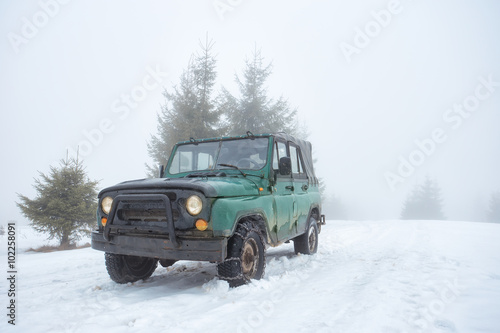 Green off-road vehicle on the snow-covered mountain © alexlukin