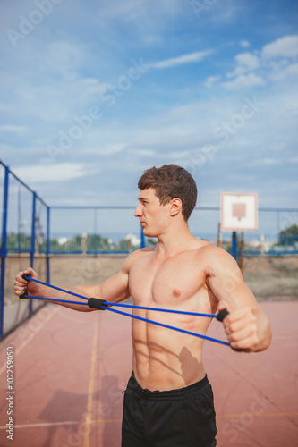 strong athletic guy sports man stretches expander