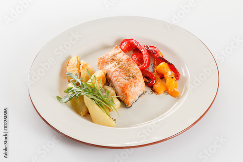 Grilled salmon fillet with vegetables, spices and arugula on a plate