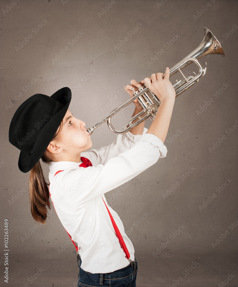little girl playing trumpet on a gray background Stock Photo