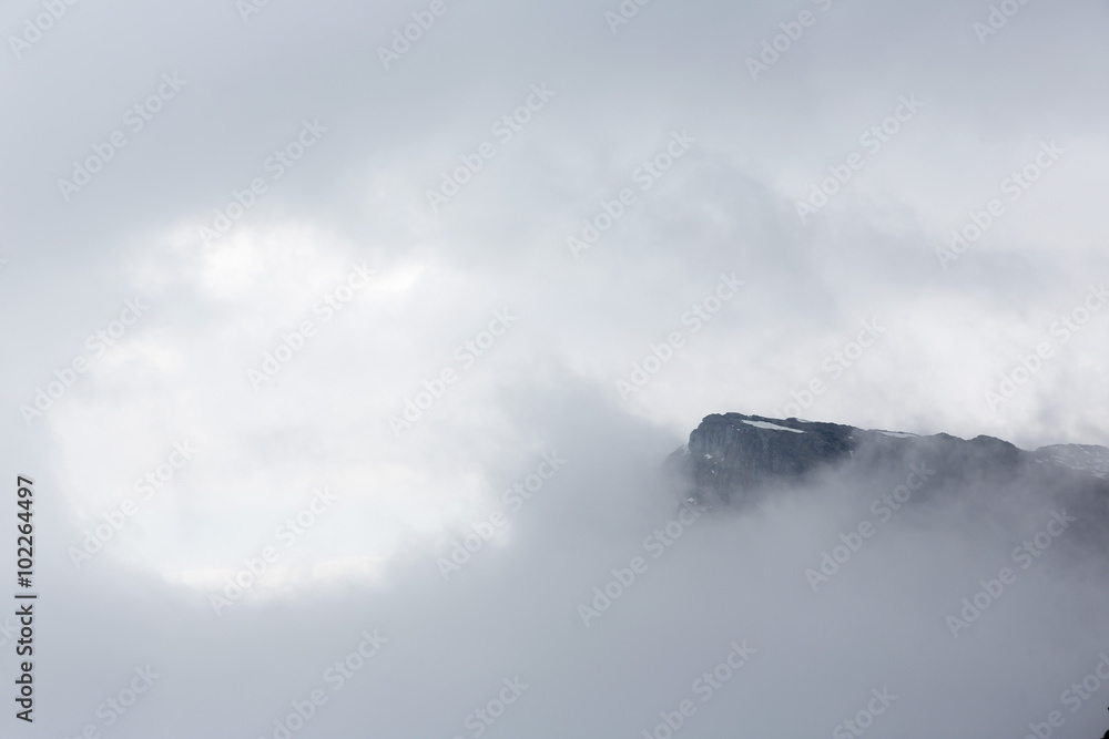 Rocky foggy mountain peak in the sky