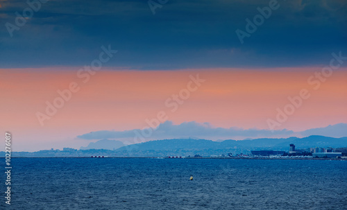 France, Nice, 2015.09.12: International airport at the sunset, mediterranean sea, lights arriving and departing aircraft, pink sky