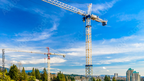 High-rise building under construction. The site with cranes against blue sky