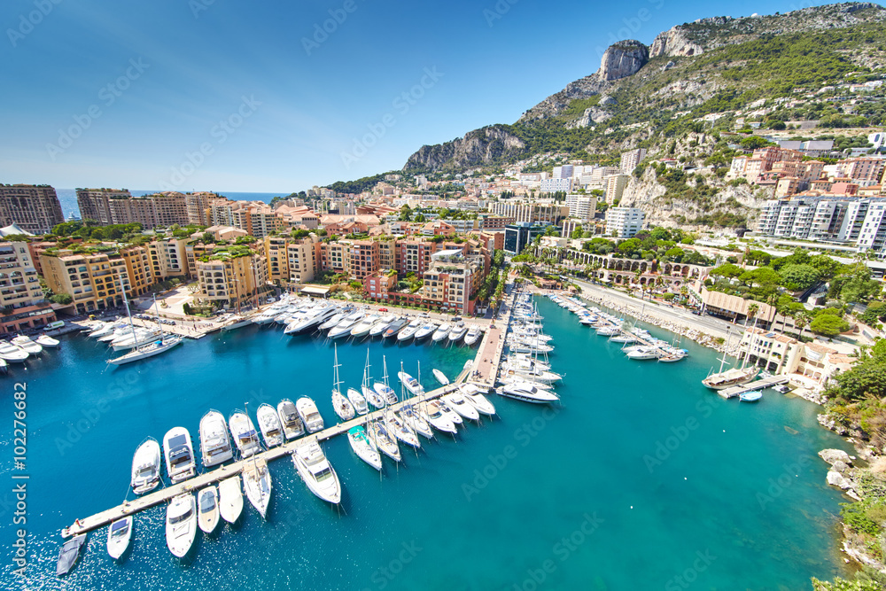 Obraz premium Monaco, Fontvieille, 29.08.2015: Port Fontvieille, panorama, widok z góry z Monaco Ville, lazurowa woda, refleksy słońca na wodzie, port, słoneczny dzień, luksusowe apartamenty, jachty, skały