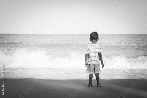 rear of little boy stanging looking the sea,black and white tone photo