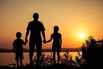 father and children playing on the coast of lake