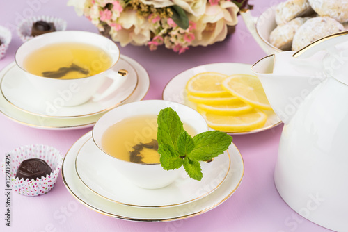 Tea cups with green tea and cookies.