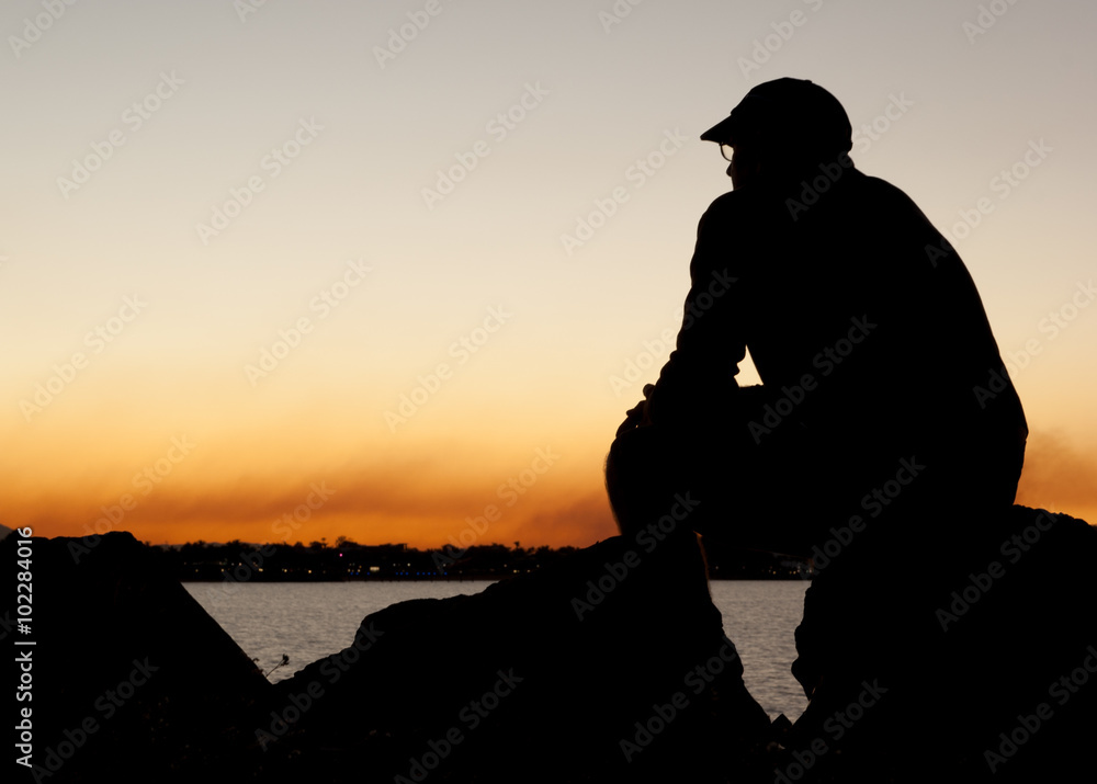 Man in silhouette sitting quietly contemplating