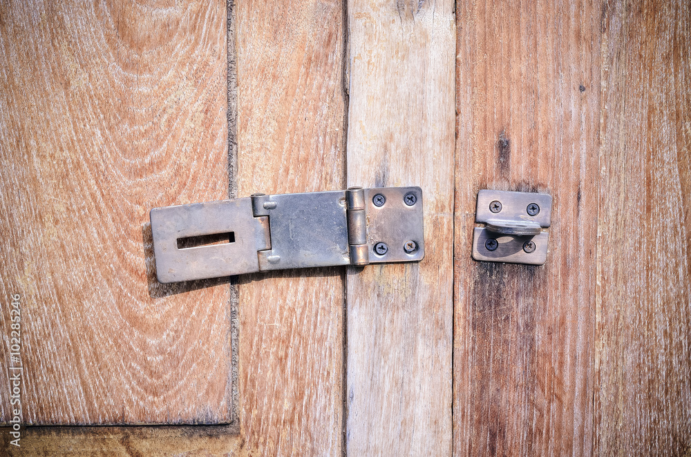 Close up of old door bolt on wooden background Close up of old door bolt on wooden background