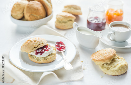 Scones with cream and fruit jam and cup of coffee