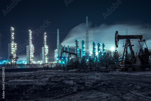Oil rigs and brightly lit industrial site at night.