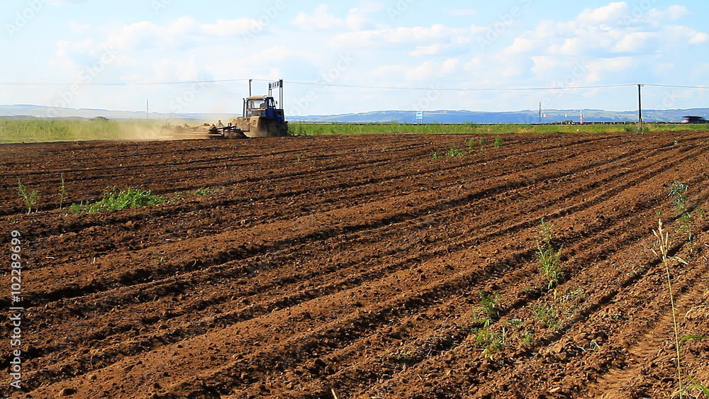 The Tractor Plows the Land. Farmer using modern farm tractor with disk harrows for harrowing field. The Tractor Plows the Land. Farmer using modern farm tractor with disk harrows for harrowing field.