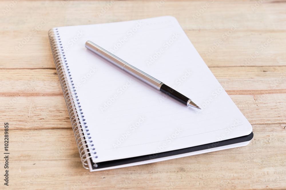 Blank white notebook with pen on wood desk. shallow depth of field Blank white notebook with pen on wood desk. shallow depth of field