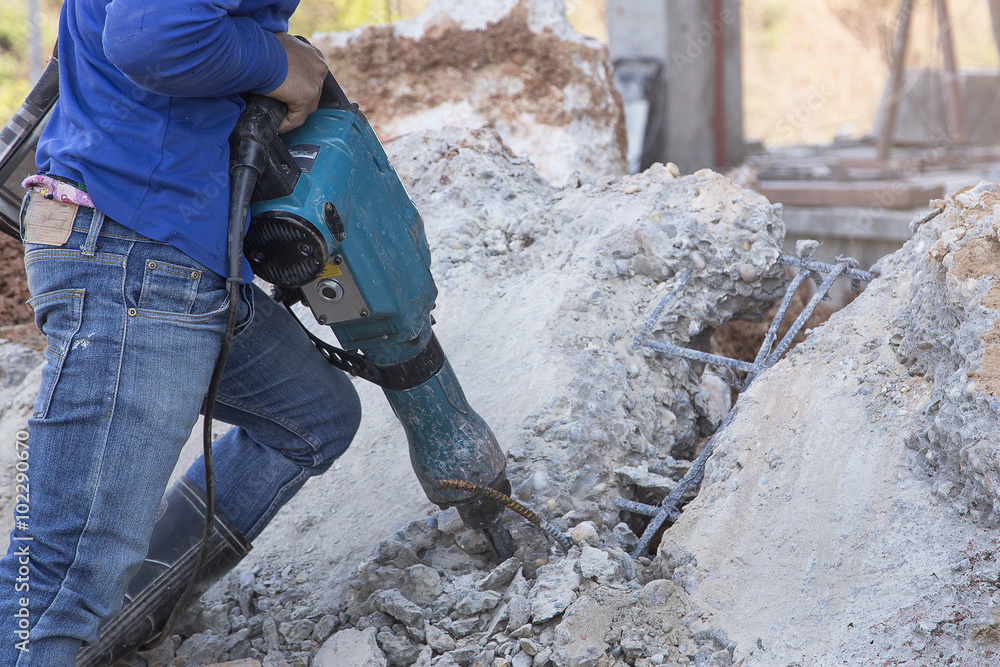 Construction worker holding jackhammer and breaking reinforced c Construction worker holding jackhammer and breaking reinforced c