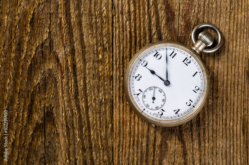 Old pocket watch and key on the wooden background with blank spa