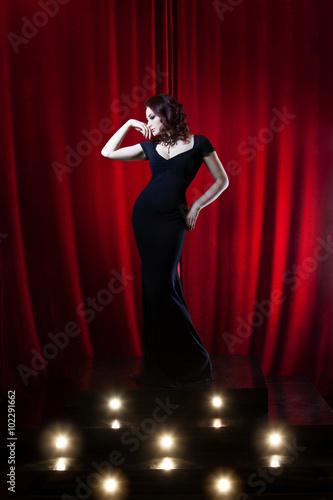 Beautiful Singing Girl on stage. Red curtain  background © Ulia Koltyrina