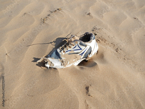 Herrenloser Turnschuh an afrikanischer Küste