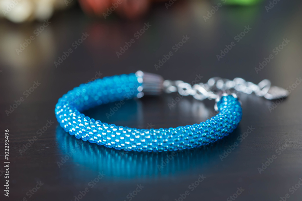 Shiny handmade bracelet from beads of turquoise color on a dark background Shiny handmade bracelet from beads of turquoise color on a dark background